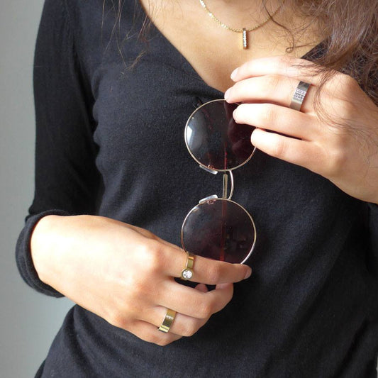 Model wearing black top with 3 Blomdahl rings on her hand. two gold rings on left and one silver ring on her right hand medical sensitive skin friendly nickel free