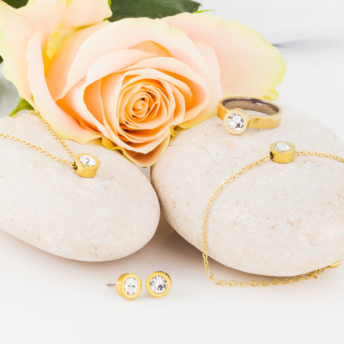 A collection of Gold Grand Bezel jewellery, consisting of a pair of earrings, necklace, bracelet and ring. Grand Bezel is a an elegant jewellery design from Blomdahl that comes with a 8mm Swarvoski crystal in the middle medical sensitive skin friendly nickel free