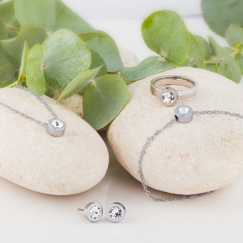 A collection of Silver Grand Bezel jewellery, consisting of a pair of earrings, necklace, bracelet and ring. Grand Bezel is a an elegant jewellery design from Blomdahl that comes with a 8mm Swarvoski crystal in the middle.